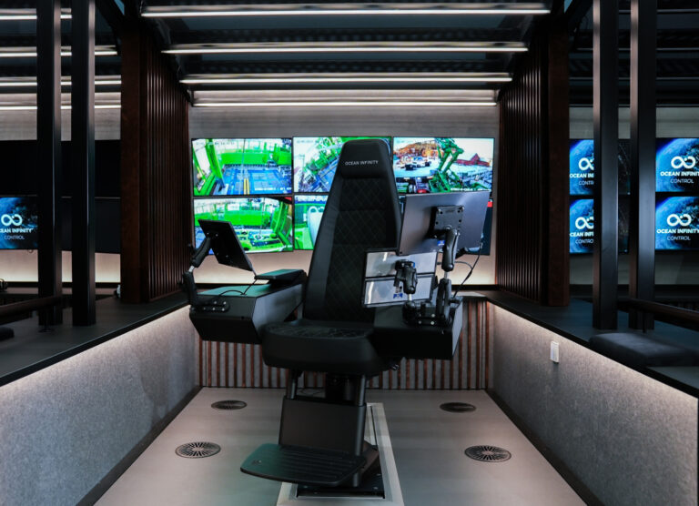 A black control room chair in an Ocean Infinity robotic ship operations center, with screens behind it.