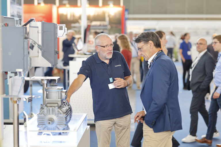 Two men discuss a piece of marine technology.