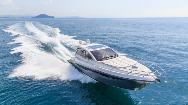 An aerial view of a luxury electric motor boat with solar panels on the roof, moves over the water at speed.