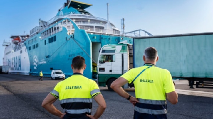 Two workers in high-vis look at a blue ferry.