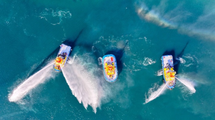 An overhead view of Latin America's first electric tug and two other ships shows the vessels floating in turquoise water.