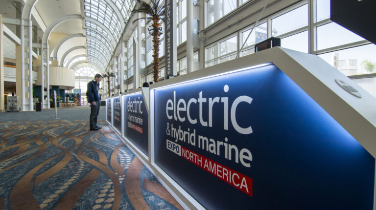 Electric & Hybrid Marine Expo North America opens this week! A man stands at the entrance desk to the Electric & Hybrid Marine Expo North America, with the exp branding on display and the convention centre lobby stretching out in the background