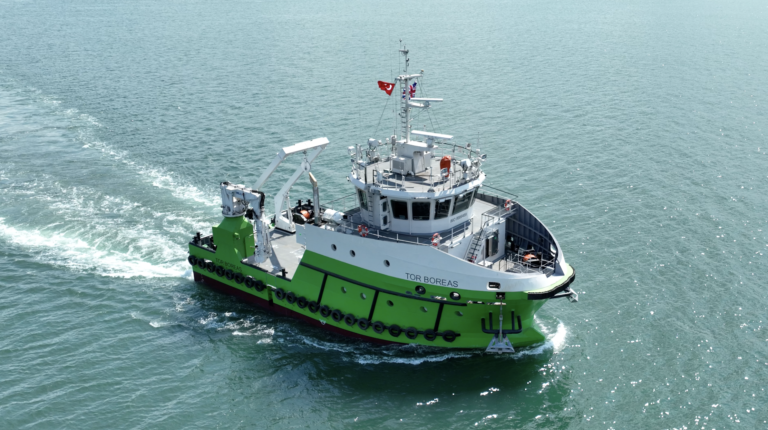 The hybrid utility vessel Tor Boreas, painted green and white, on calm seas