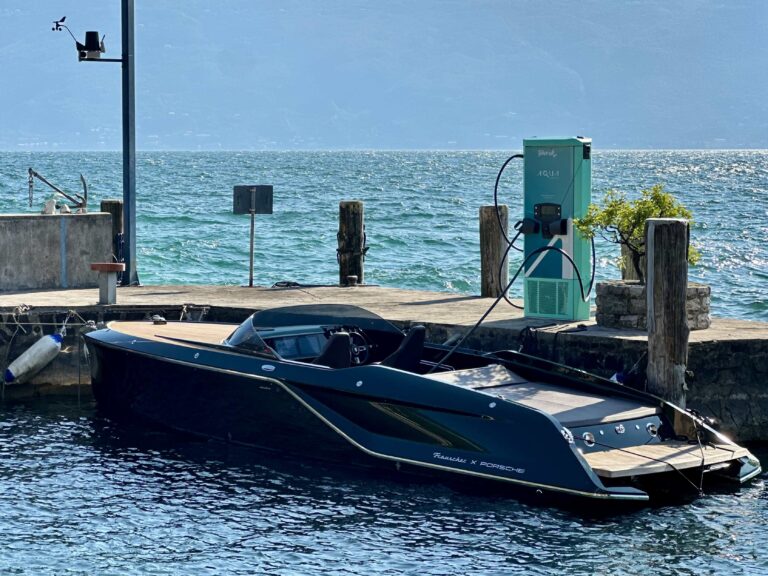 The new Aqua Superpower marine fast charger installed at Lake Garda, on a small wooden jetty on green-blue water and under a blue sky