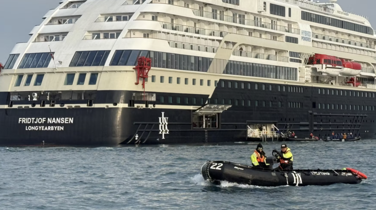 A small outboard boat moves alongside a larger expedition touring vessel