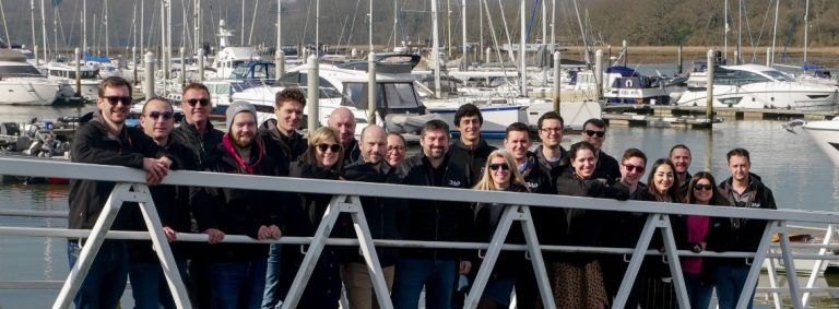 Representatives of RAD Propulsion pose in front of the harbor.