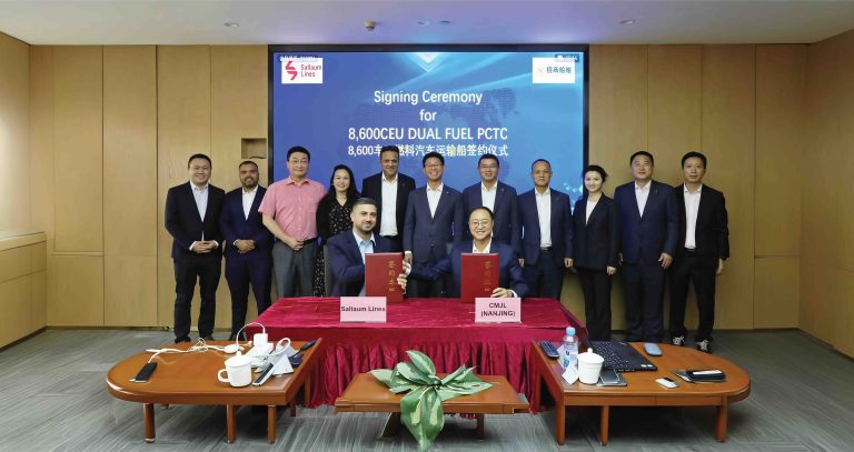 Representatives of Sallaum Lines and China Merchants Shipbuilding stand in front of a large screen to mark the singing of the contract.