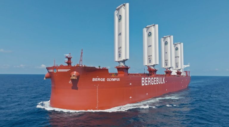 A ship with WindWings propulsion technologies sails through calm waters on a sunny day.
